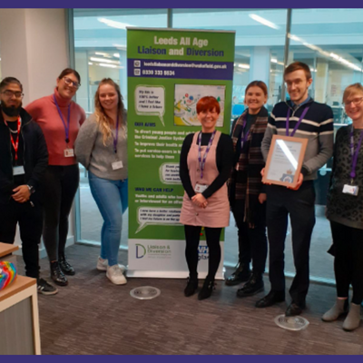 Leeds team standing in front of the Liaison and Diversion banner holding an award